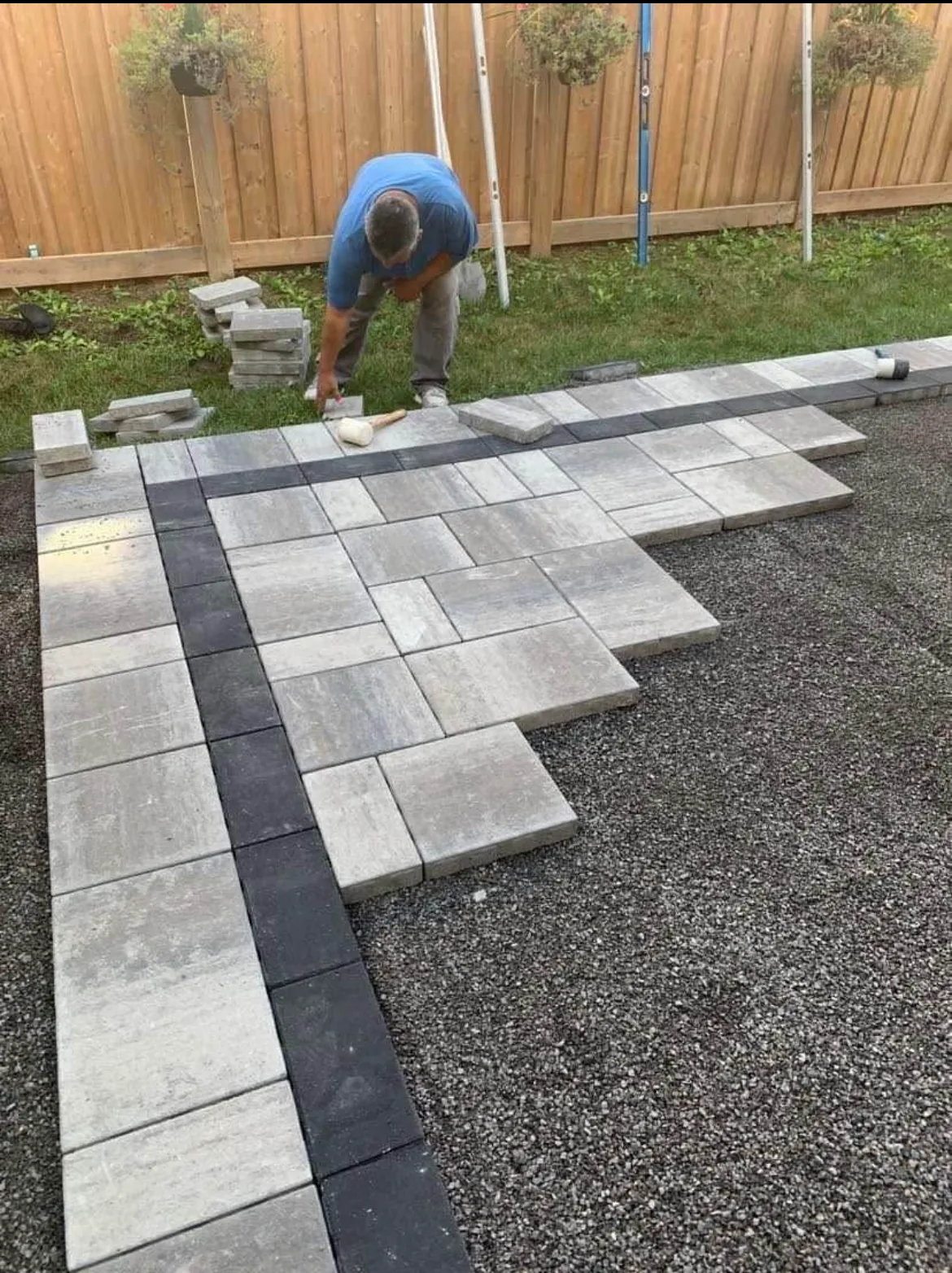 Paver patio being laid with a charcoal banding course along the edge