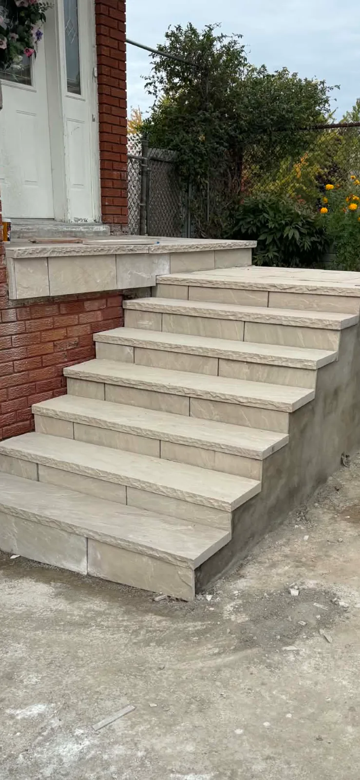 Finished stone steps beside a freshly parged foundation wall